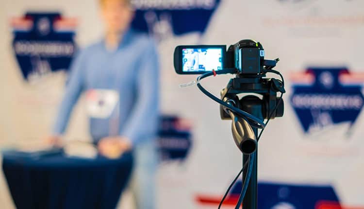 A man is standing in front of a video camera.