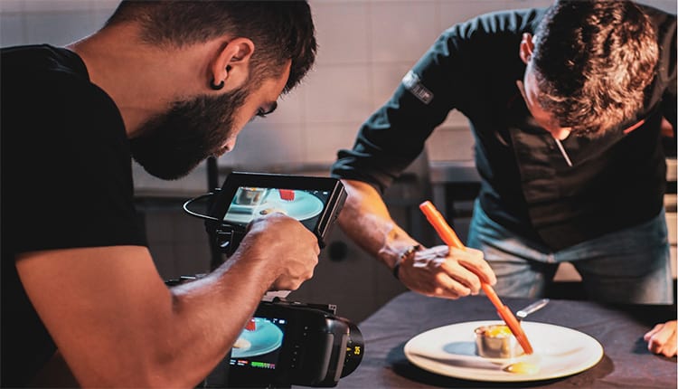 Taking a video of a man preparing a plate of food.