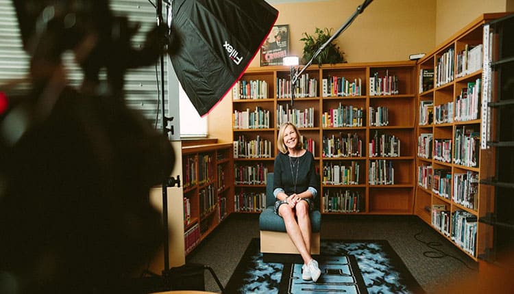 Taking a vidoe of a woman sitting on a chair in a library.