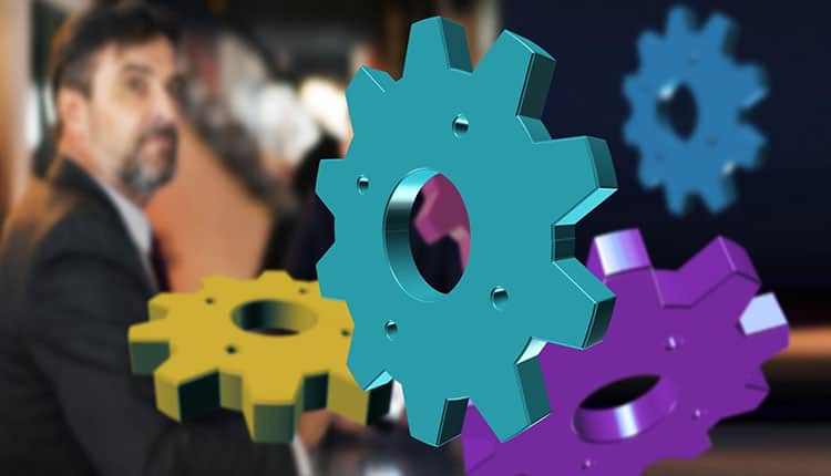 A man is standing behind a group of colorful gears.