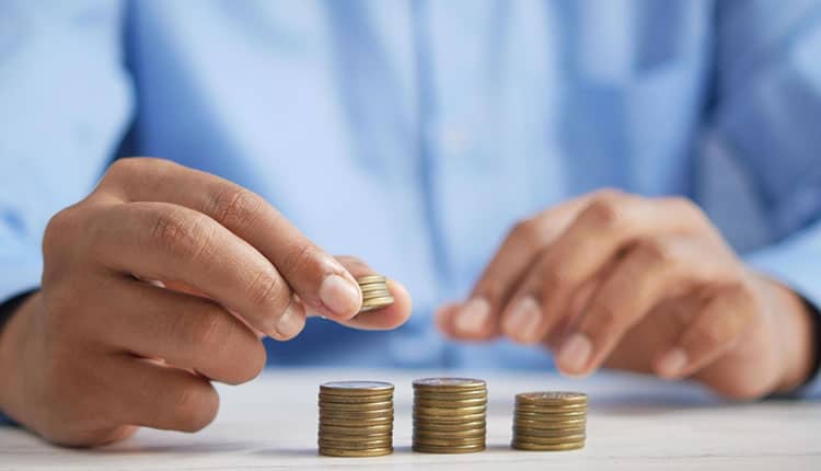 A man is putting coins on top of a stack of coins.