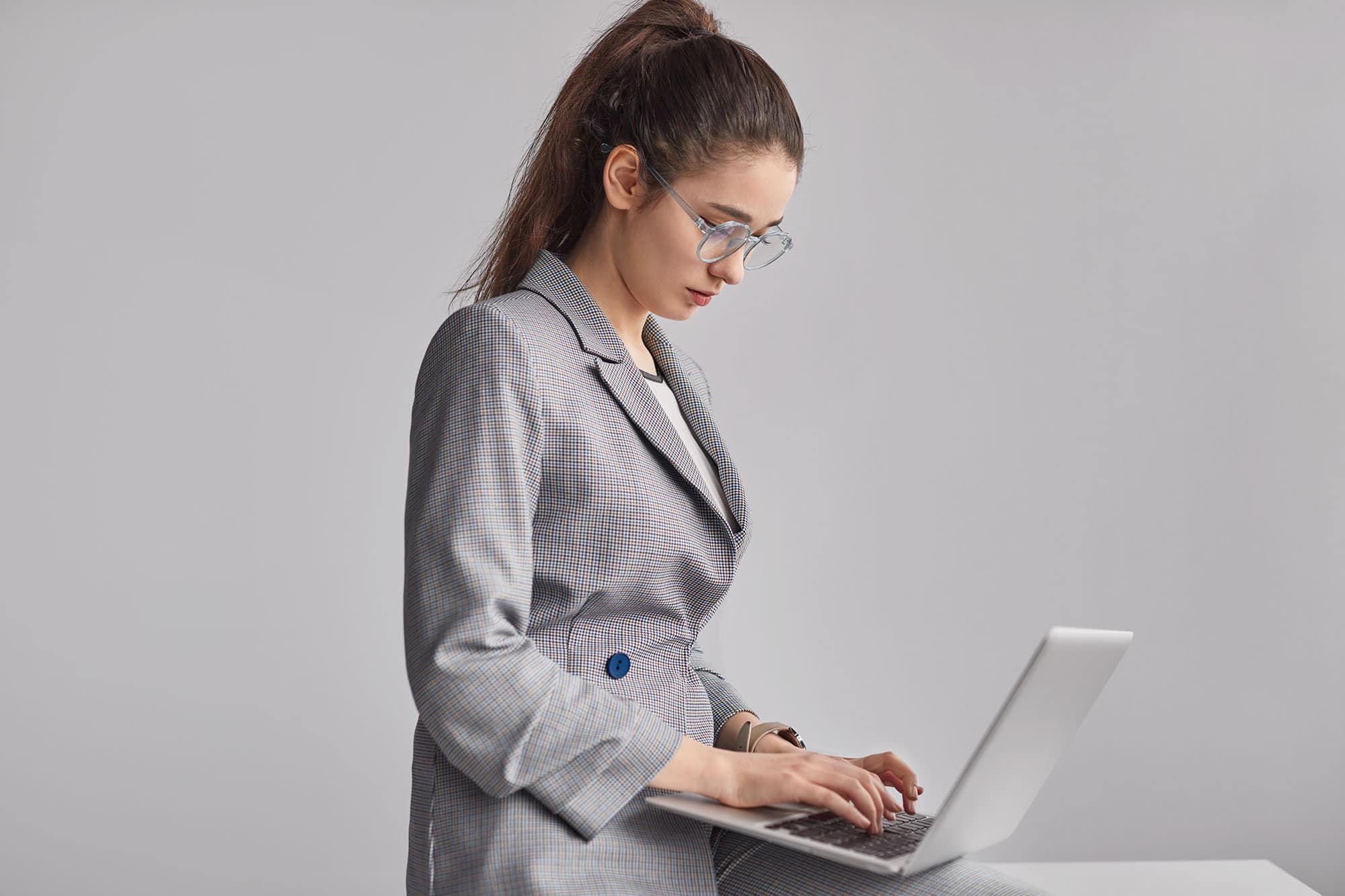 A woman in a business suit is using a laptop.