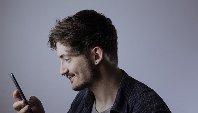 A smiling man looking at his smartphone.