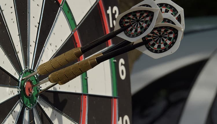 A dartboard with three darts neatly clustered around the bullseye.