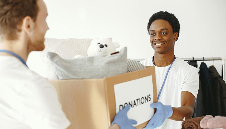 A man holding out a donation box ang giving to the other person