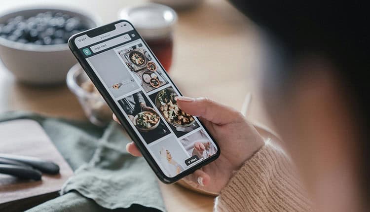 A person holding a smartphone while browsing food photos on an app. 