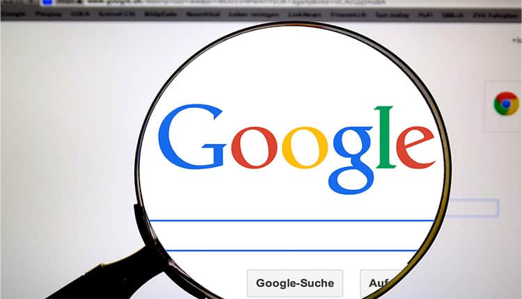 A magnifying glass is focusing on the Google search engine logo displayed on a computer screen.