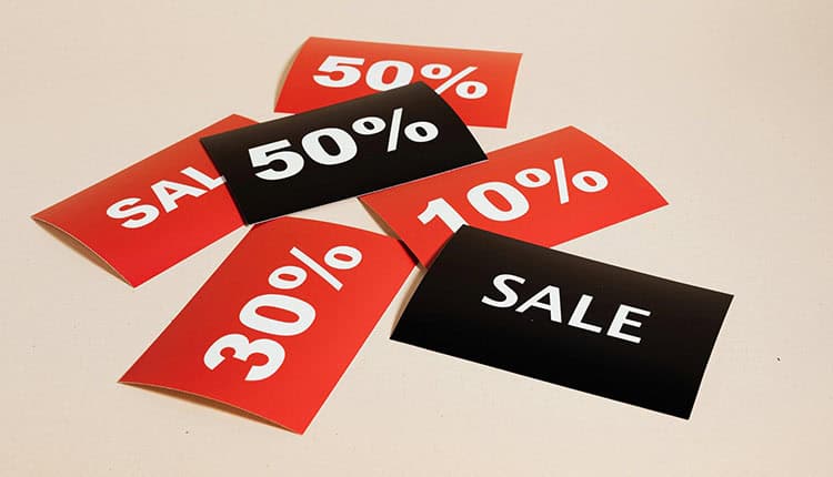 Red and black sale signs with discount percentages of 10%, 30%, and 50% displayed on a beige surface.