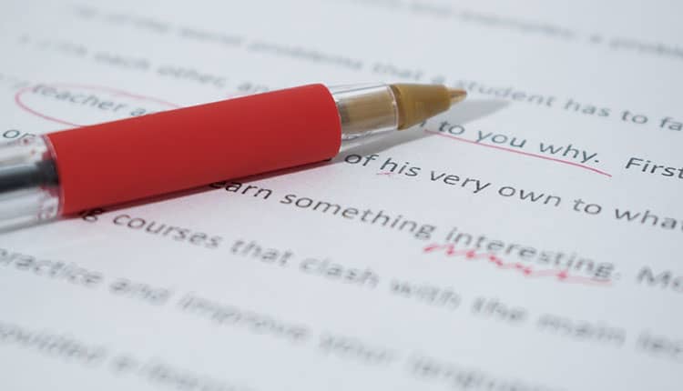 A red pen lies on a printed paper with text and red markings, indicating corrections or edits.