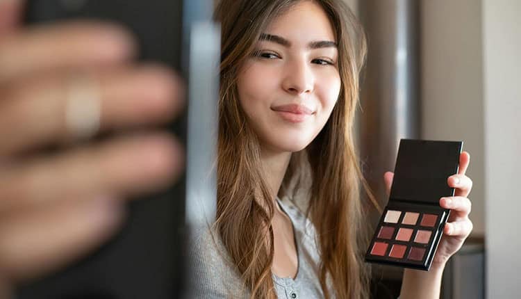 Person holding an eyeshadow palette while taking a selfie.