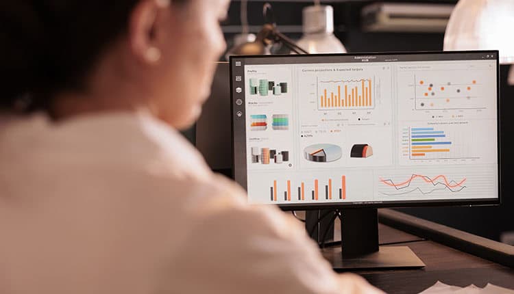 Woman analyzing company marketing project revenue statistics on computer screen, working on business research in coworking space at night. Corporate worker checking analytics