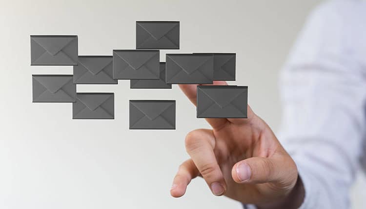 A person’s hand points towards floating digital envelope icons, representing emails or messages