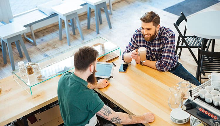 young man drinking coffee and talking to barista