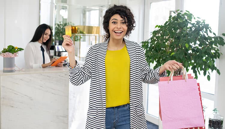 A woman holding a discount card and shopping bags.