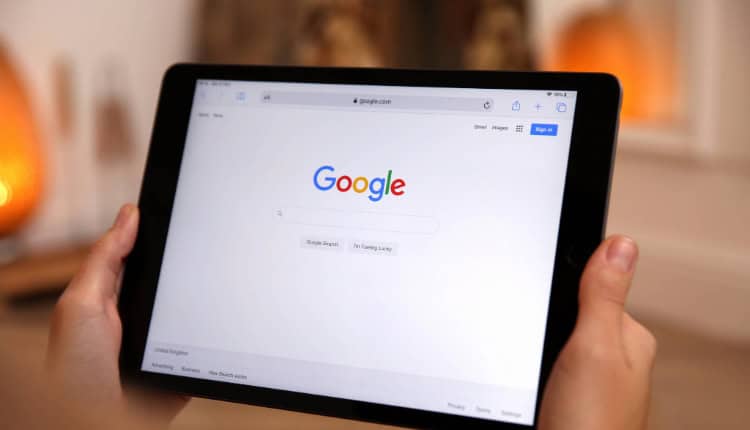 A person holds a tablet displaying the Google homepage,