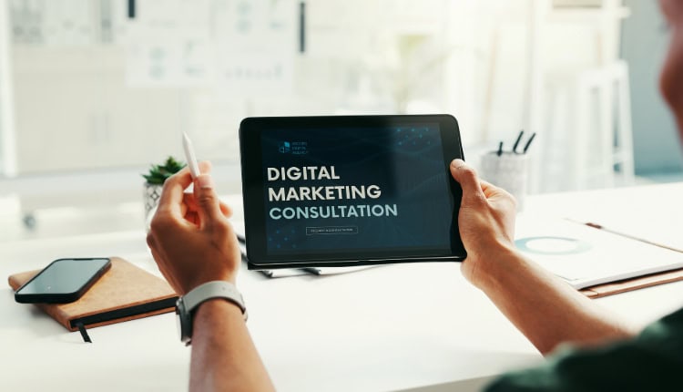 Person holding a tablet displaying the text "Digital Marketing Consultation"