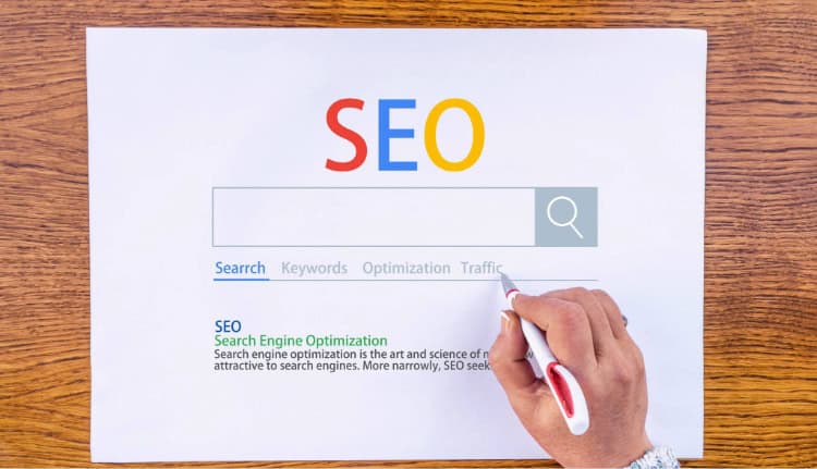 A person underlines the word "Search" on a printed SEO concept diagram showing a search bar