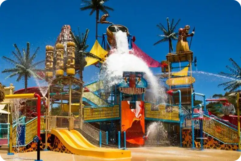 Kahuna Falls water play structure featuring a large tipping bucket, slides, and tiki-themed decorations.
